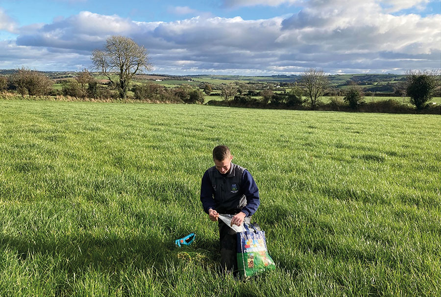 Photo of PhD student Chris Heffernan collecting pasture samples from a commercial dairy farm