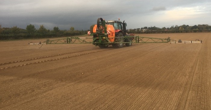 tractor and spray apply a pre emergence herbicide to sown field