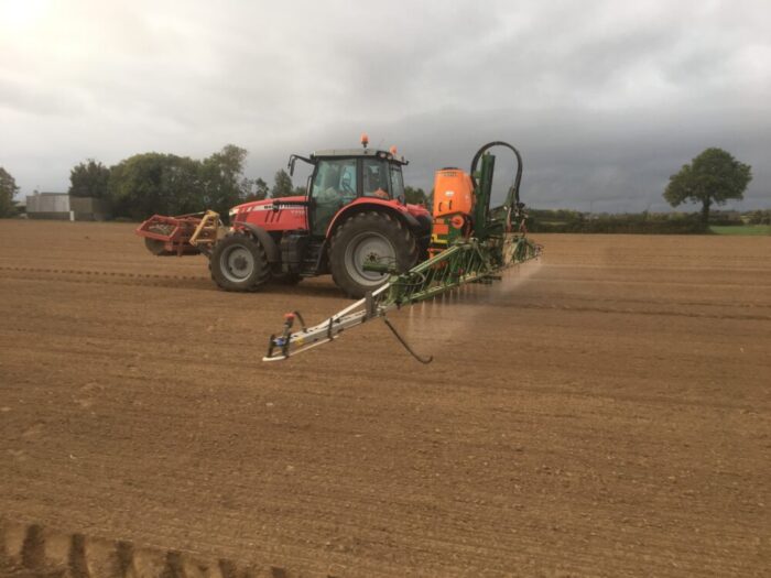 A tractor applying applying a pre emergence herbicide in a crop of winter barley
