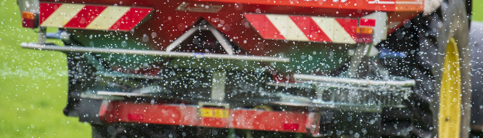 A close up of fertiliser leaving a fertiliser spreader
