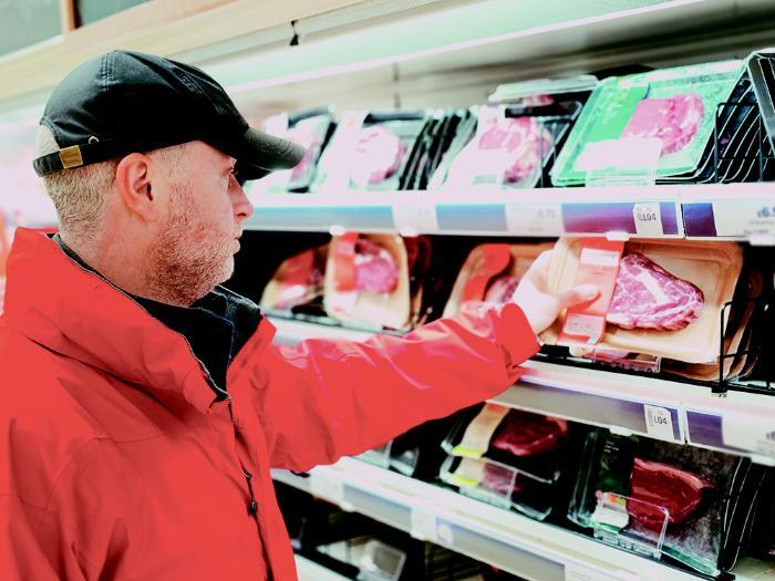 A customer examining meat on a shelf in a shop