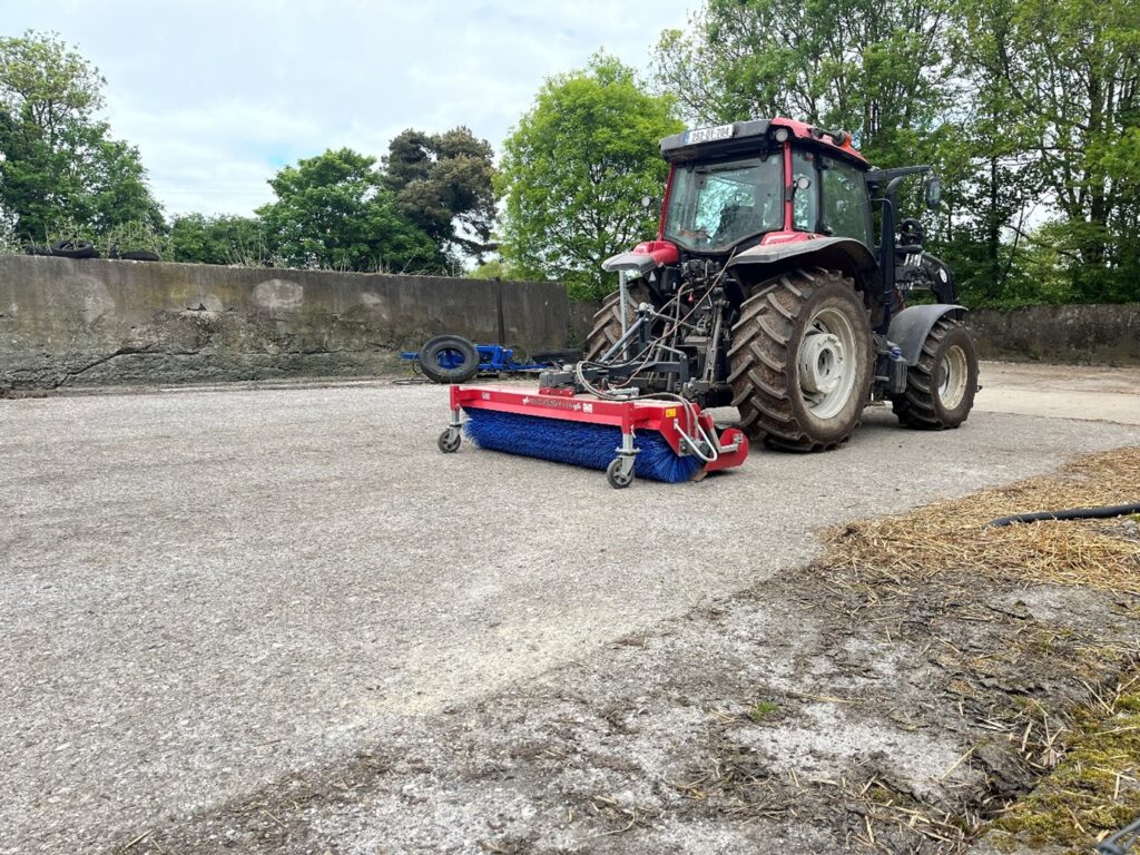 Bucket & brush rear mounted on a tractor in cleaned yard