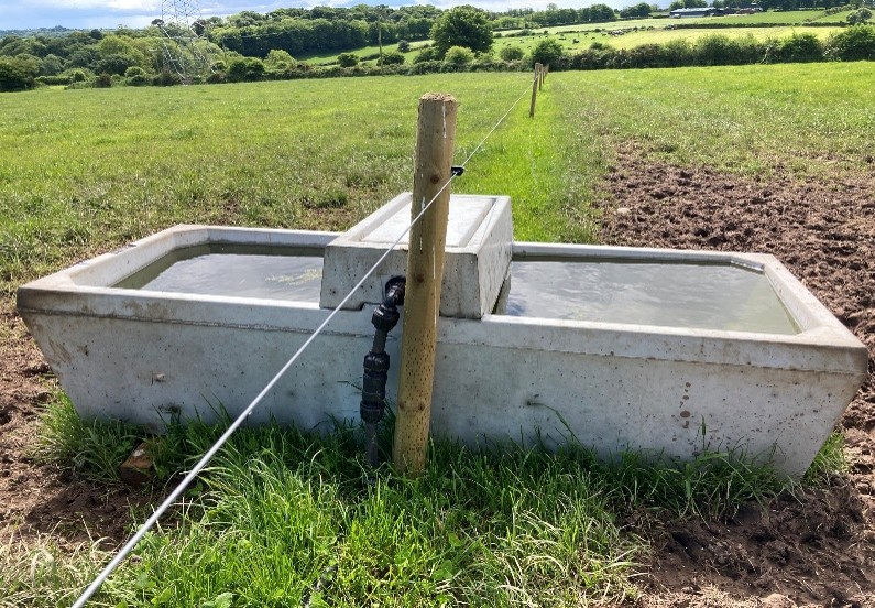 Concrete water trough in paddocked field