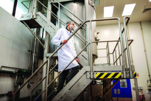 a scientist in a white lab coat walking up steps in a lab