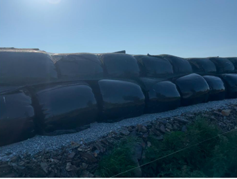 Bales protected by net and stacked no more than 2 high on hardcore