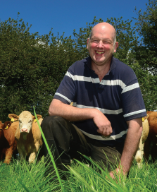 John Pringle in grass field with his herd of suckler cows