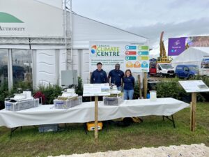 Teagasc staff at the Climate Centre stand standing behind a table with three chambers and in front of a poster board about the Climate Centre